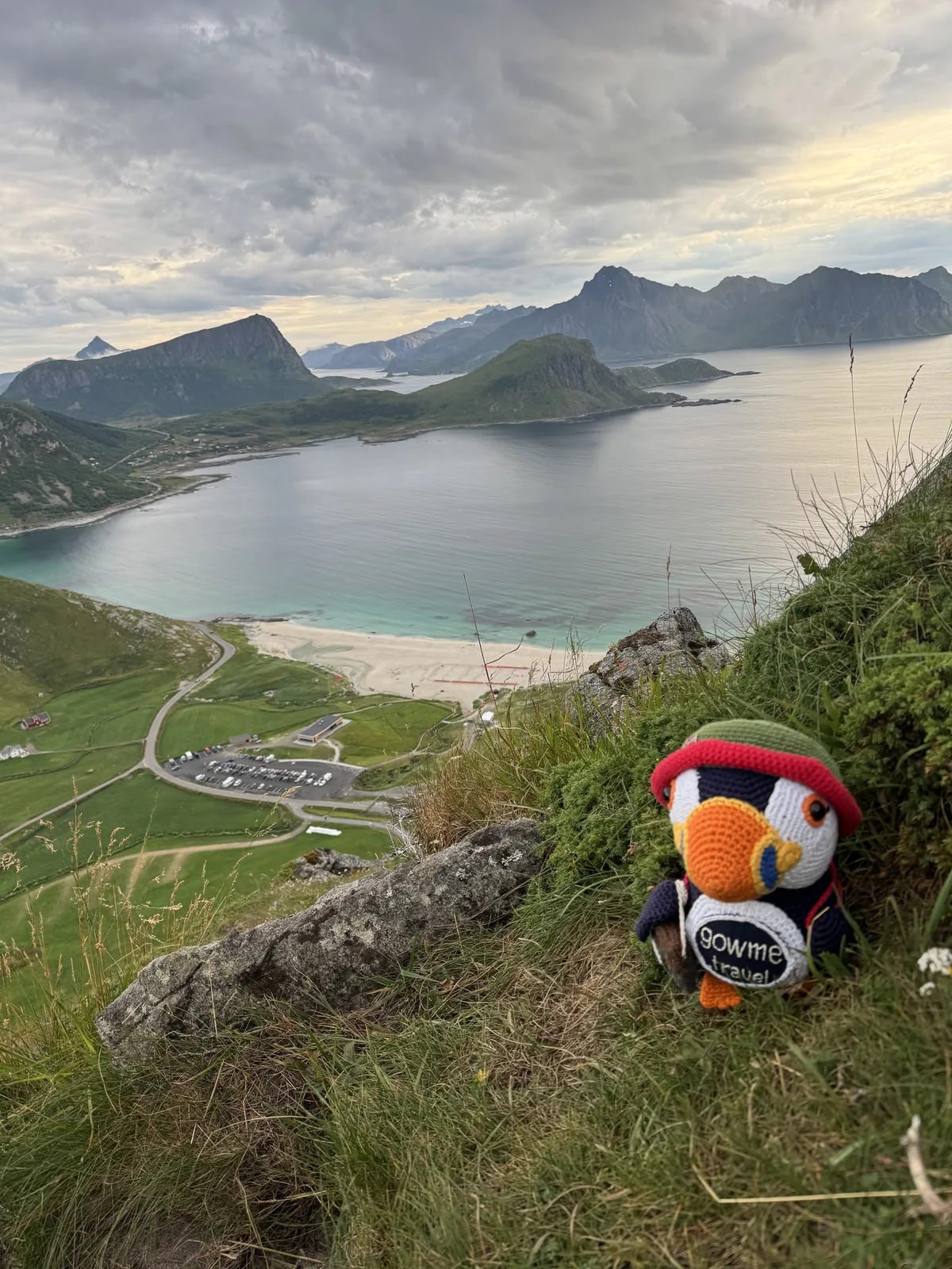 Our Gowme.travel mascot above Haukland Beach, looking down over the white sand, turquoise bay and the car park, Lofoten