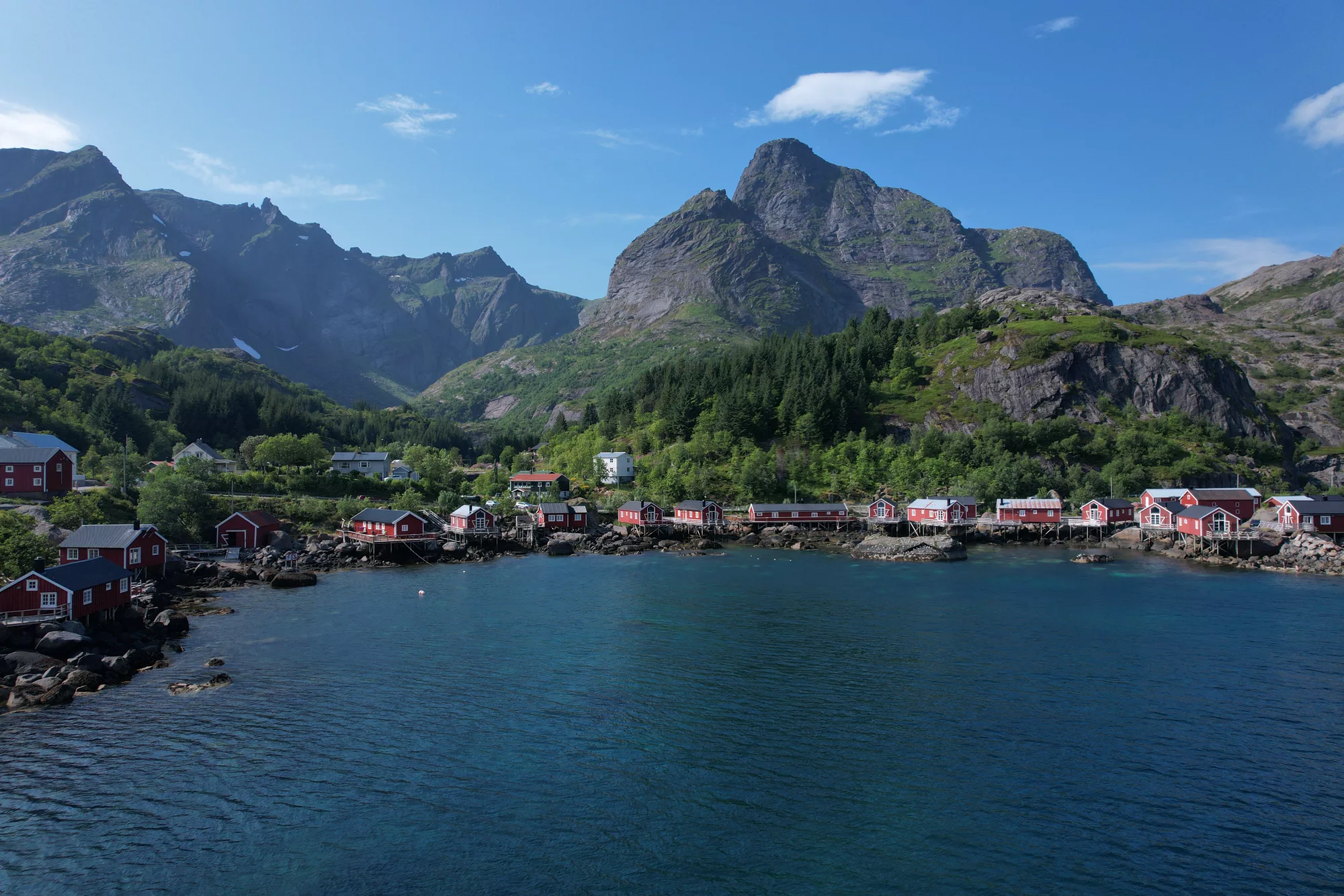 Our aerial photo of Nusfjord — red rorbuer along the harbour beneath steep Lofoten mountains, Norway