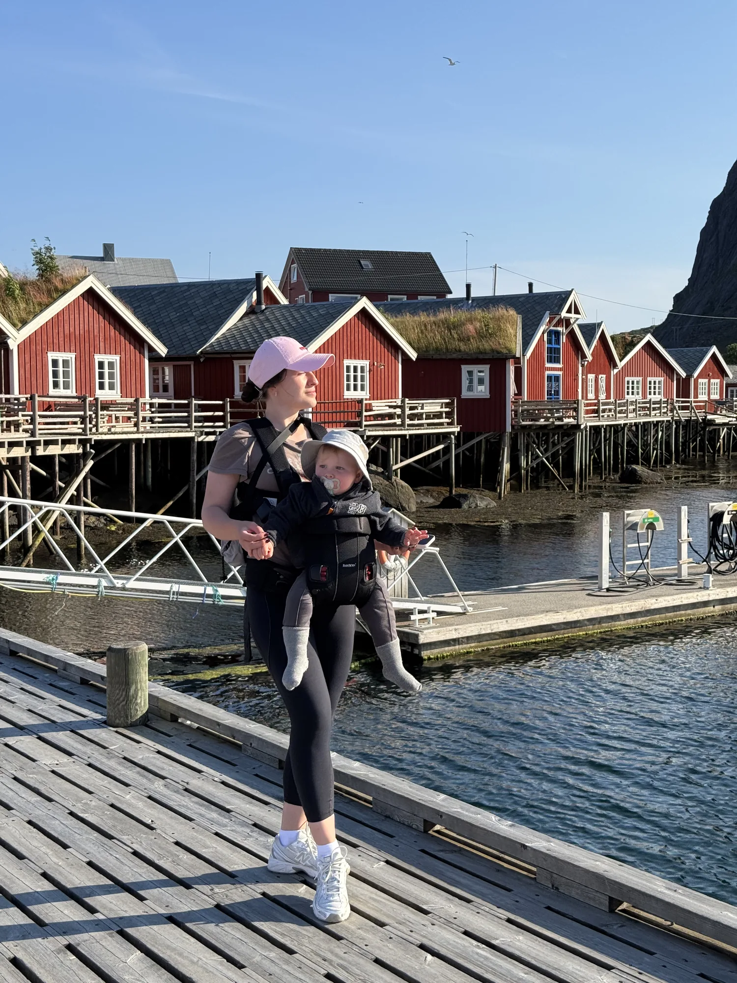 A Gowme.travel author carrying our child in a carrier backpack on the dock by the rorbuer of Reine, Lofoten